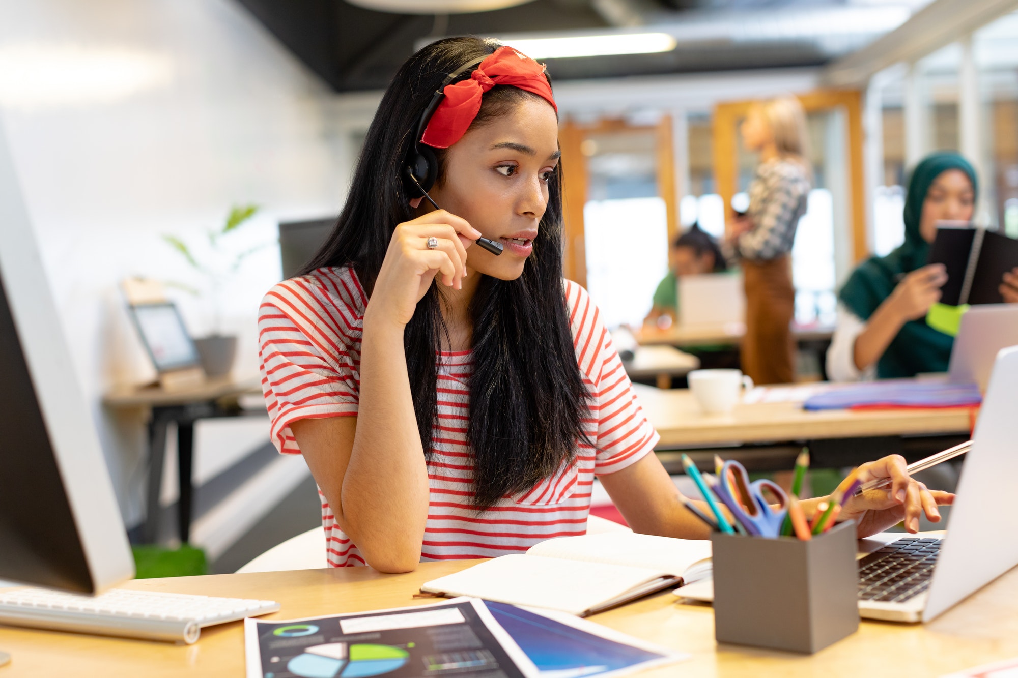 beautiful-mixed-race-female-customer-service-executive-talking-on-headset-and-working-on-laptop.jpg